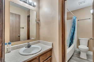 Full bathroom featuring hardwood / wood-style flooring, vanity, shower / tub combo, and toilet