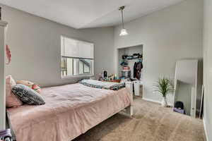 Carpeted bedroom featuring vaulted ceiling and a closet