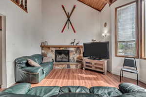 Living room featuring wood-type flooring, a fireplace, high vaulted ceiling, and wooden ceiling