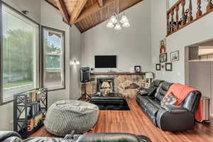 Living room featuring hardwood / wood-style floors, a fireplace, a chandelier, wooden ceiling, and beam ceiling