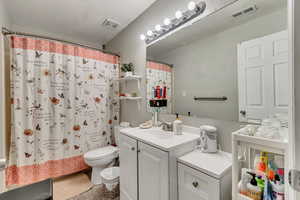 Full bathroom featuring shower / bath combination with curtain, vanity, and toilet