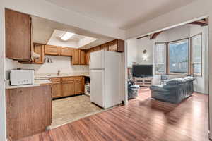 Kitchen with white fridge, sink, and light wood-type flooring