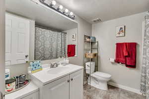 Bathroom featuring vanity, a textured ceiling, and toilet