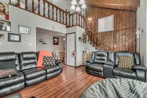 Living room featuring wood-type flooring, high vaulted ceiling, wooden ceiling, wooden walls, and beam ceiling