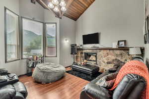 Living room with wood-type flooring, a fireplace, lofted ceiling with beams, and wooden ceiling