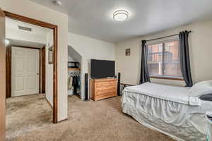 Bedroom with light colored carpet and a closet