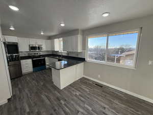 Kitchen featuring stainless steel appliances, white cabinetry, sink, and kitchen peninsula