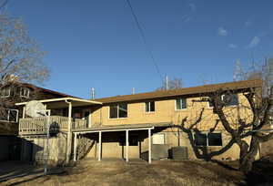 Back of house with cooling unit and a wooden deck