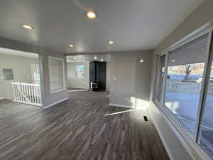 Unfurnished living room featuring dark hardwood / wood-style floors, a wood stove, and electric panel