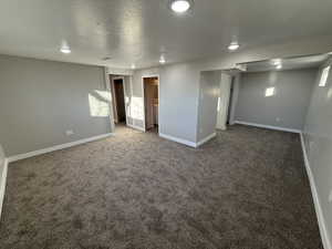 Interior space featuring dark carpet and a textured ceiling