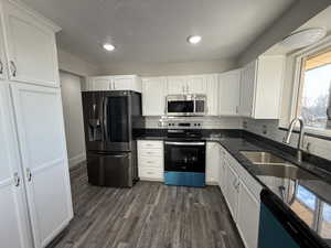 Kitchen featuring white cabinetry, sink, decorative backsplash, stainless steel appliances, and dark wood-type flooring