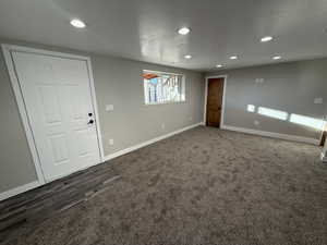 Empty room featuring dark colored carpet and a textured ceiling