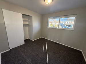 Unfurnished bedroom featuring dark carpet and a closet