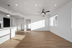 Unfurnished living room with sink, hardwood / wood-style floors, and ceiling fan