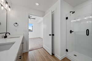 Bathroom with a shower with door, vanity, and hardwood / wood-style floors