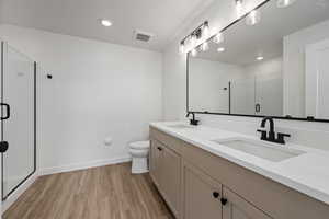 Bathroom with vanity, hardwood / wood-style floors, an enclosed shower, and toilet