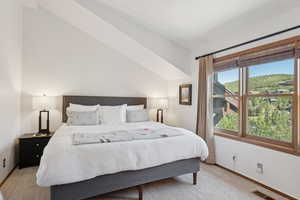 Bedroom with light carpet and vaulted ceiling