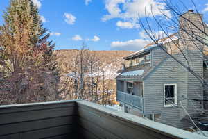 Snow covered back of property with a mountain view and central AC