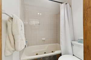 Full bathroom featuring a combined bath / shower with jetted tub and toilet