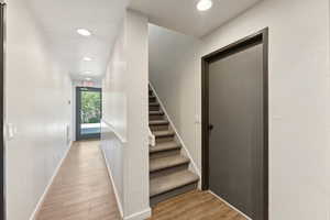 Stairs with wood finished floors and recessed lighting