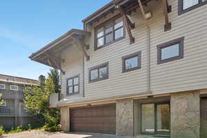 View of side of home featuring stone siding, a garage, and concrete driveway