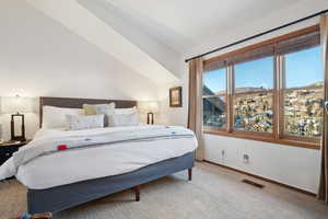 Carpeted bedroom featuring vaulted ceiling