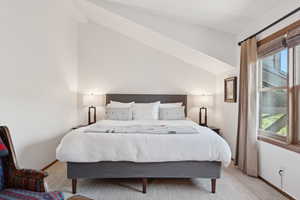 Bedroom featuring carpet flooring, multiple windows, and lofted ceiling