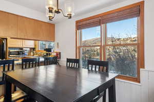 Dining space featuring a notable chandelier, wood walls, and a healthy amount of sunlight