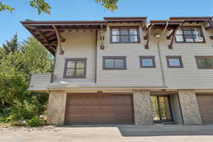 View of front facade featuring stone siding, a garage, and driveway