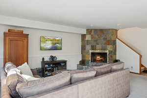 Living area with a large fireplace, light colored carpet, and stairs