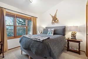 Bedroom with light carpet and vaulted ceiling