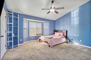 Bedroom with lofted ceiling, ceiling fan, and carpet flooring