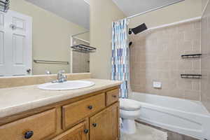 Full bathroom featuring vanity, shower / bath combination with curtain, and toilet