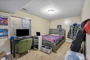 Bedroom featuring light colored carpet and a textured ceiling