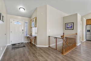 Foyer entrance with wood-type flooring and vaulted ceiling