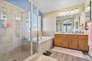 Bathroom with shower with separate bathtub, vaulted ceiling, vanity, hardwood / wood-style flooring, and ceiling fan