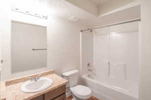 Full bathroom featuring a textured ceiling, toilet, vanity, and shower / tub combination