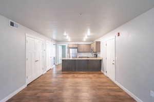 Kitchen with sink, kitchen peninsula, appliances with stainless steel finishes, and dark hardwood / wood-style flooring