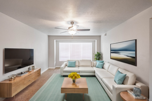 Carpeted living room featuring ceiling fan and a textured ceiling
