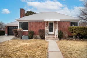 View of front of home with a garage, a front lawn, and central AC