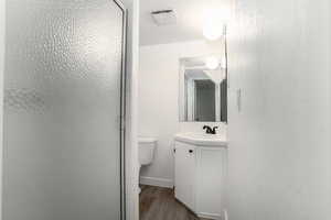 Bathroom featuring hardwood / wood-style floors, toilet, vanity, and walk in shower