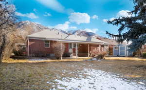 Snow covered house featuring a storage shed and a mountain view