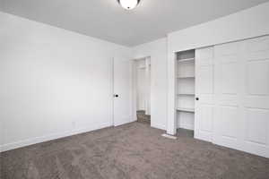 Unfurnished bedroom featuring a closet and dark colored carpet