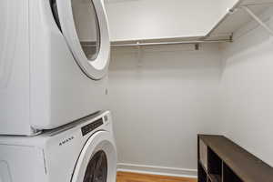 Washroom featuring stacked washer and dryer and light hardwood / wood-style flooring