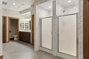 Bathroom featuring walk in shower, vanity, and toilet