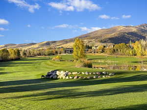 Surrounding community with a mountain view and a lawn