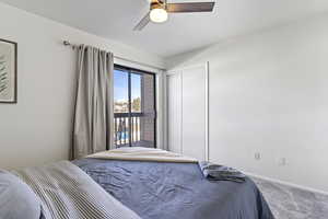 Carpeted bedroom with access to outside, ceiling fan, and a closet