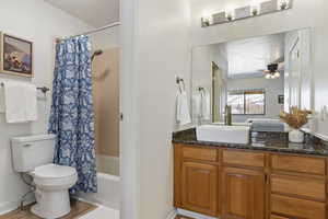 Full bathroom featuring toilet, a textured ceiling, vanity, shower / bath combo, and ceiling fan