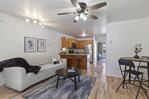 Living room featuring ceiling fan, a textured ceiling, and light wood-type flooring