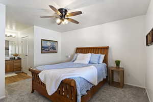 Bedroom featuring light carpet, connected bathroom, a closet, and ceiling fan